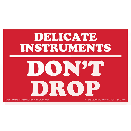 Red warning label with white text reading ’DELICATE INSTRUMENTS DON’T DROP’