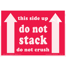 Red warning label with white text reading ’this side up do not stack do not crush’ and upward-pointing arrows.